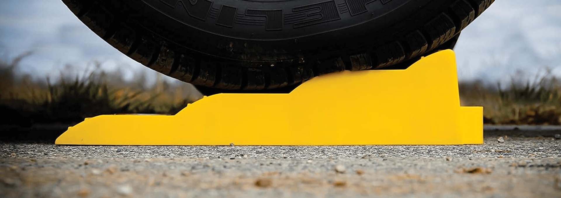 A campervan wheel balanced on a yellow levelling chock