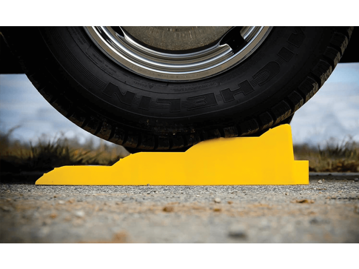 A campervan wheel balanced on a yellow levelling chock