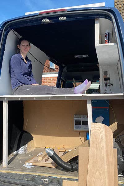 Maddy sat in the back of the Mercedes Sprinter, on top of the bed that they're in the process of making