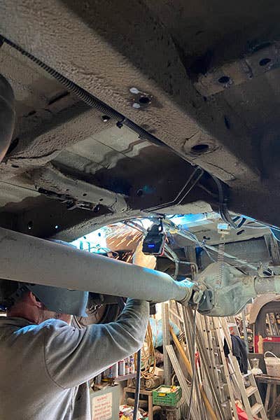 An image showing Mike, a friend of Al and Maddy, working on the underside of their Mercedes Sprinter campervan