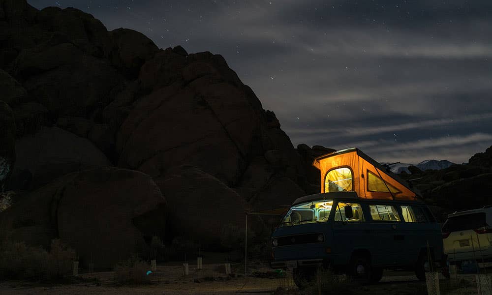 A VW T25 with a pop-top roof parked up at night. Photo by Tommy Lisbin, via Unsplash
